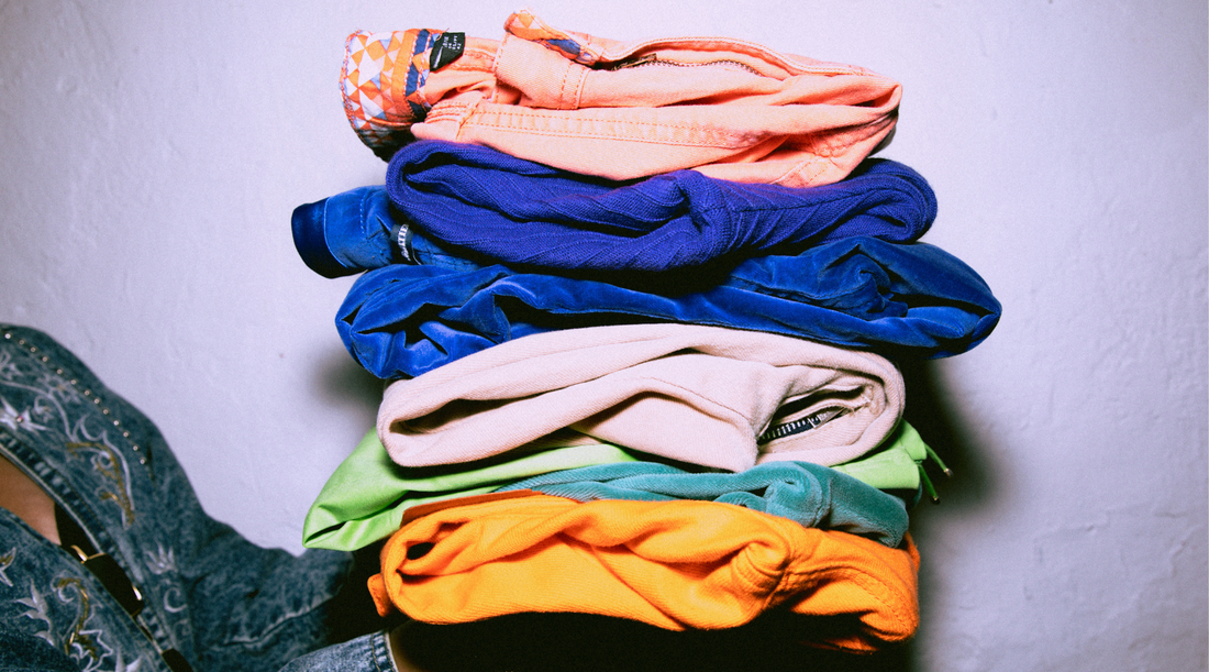 A collection of folded second-hand shirts discovered during a thrift shopping adventure, showcasing vibrant colors and patterns.